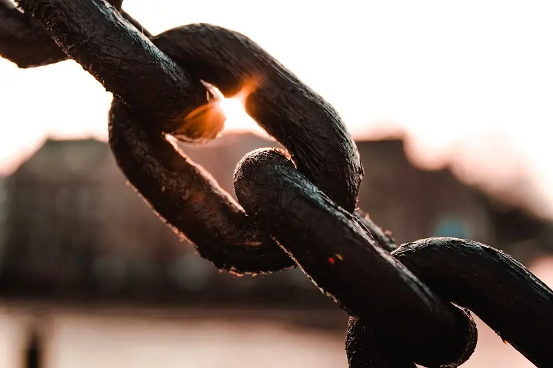 rusty chain with sun peeking through a link