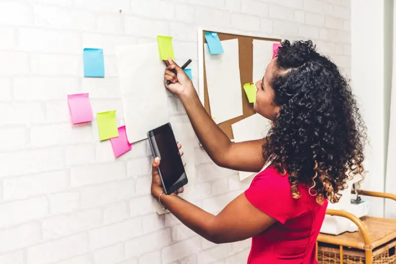 woman looking at sticky notes on a white brick wall