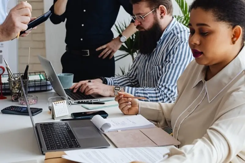 people working on laptops and paper at desks