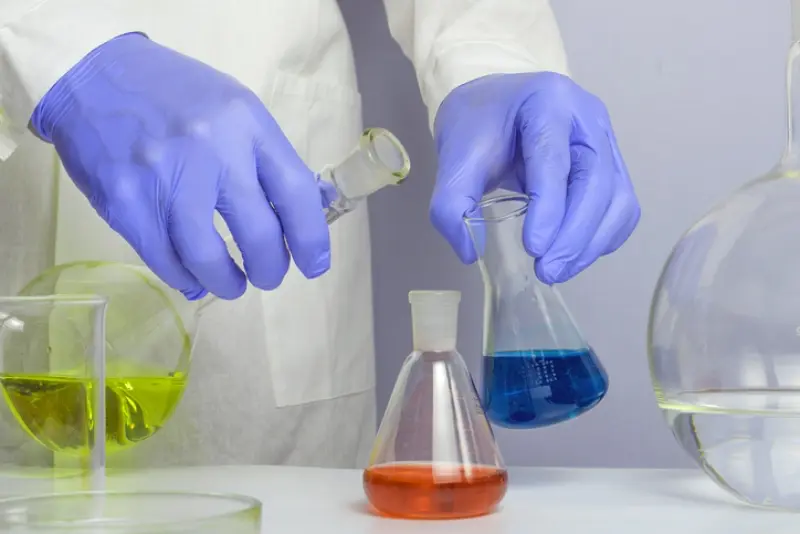 gloved hands mixing liquids