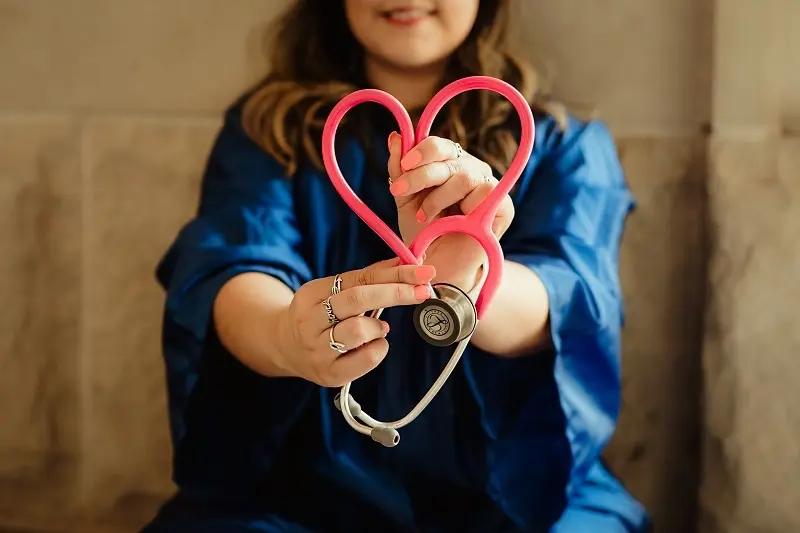 woman holding stethoscope in heart shape