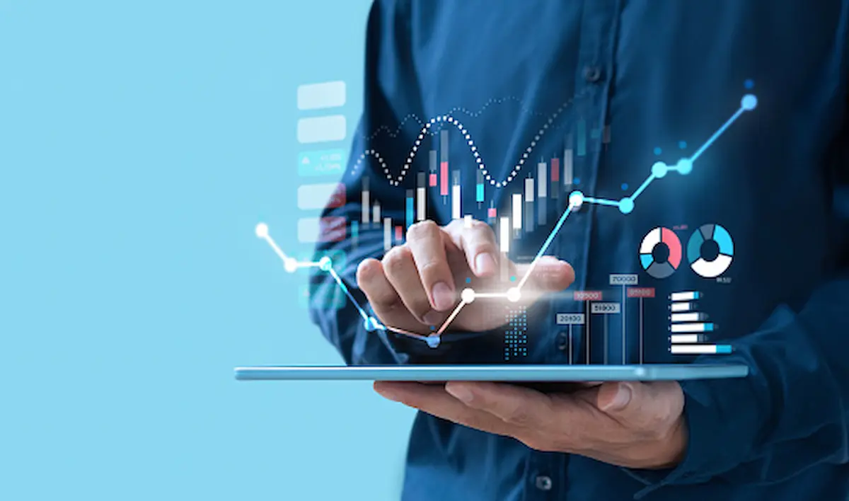 man typing on digital tablet with holographic trends and statistics images hovering above