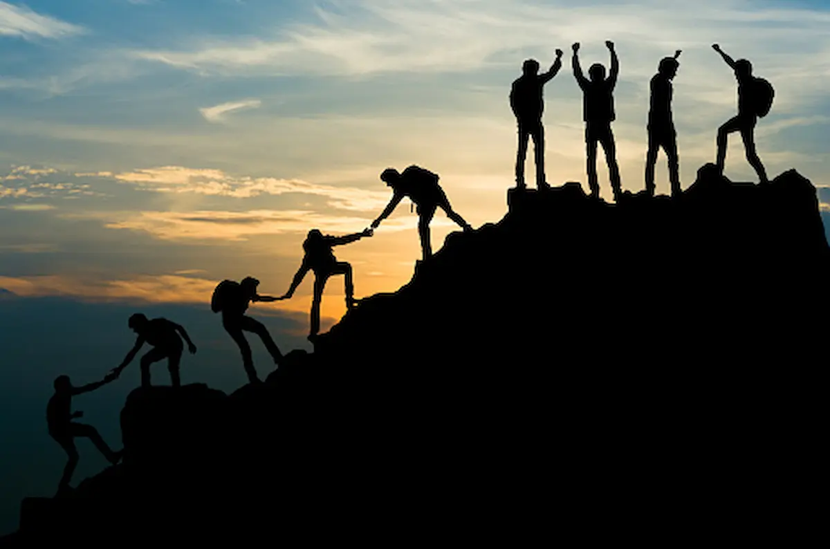 help_succeed silhouettes working together and celebrating climbing a mountain